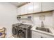 Well-equipped laundry room with modern washer, dryer, sink and ample storage at 8269 Skye Peak St, Las Vegas, NV 89166