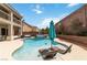 Beautiful pool with chaise lounges and blue umbrella, surrounded by lush landscaping and a brick wall at 8275 Old Creek Ranch St, Las Vegas, NV 89139