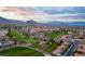 Stunning aerial view of a golf course community with picturesque mountain backdrop at sunset at 8629 Prairie Hill Dr, Las Vegas, NV 89134