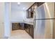 Charming kitchenette with dark wood cabinets, stainless steel fridge, granite countertop, and tile flooring at 8665 Jerlyn St, Las Vegas, NV 89113