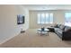 Cozy living room with neutral carpet, a comfortable gray sofa, and a wall-mounted TV at 8665 Jerlyn St, Las Vegas, NV 89113