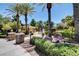 Community pool area with lush landscaping and mature palm trees on a sunny day at 9303 Gilcrease Ave # 2198, Las Vegas, NV 89149