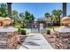 Community pool entrance with secure gate surrounded by lush landscaping and palm trees at 9303 Gilcrease Ave # 2198, Las Vegas, NV 89149
