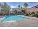 Community pool with crystal clear water, palm trees and manicured landscaping under a bright sky at 9303 Gilcrease Ave # 2198, Las Vegas, NV 89149