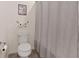 Simple bathroom with a toilet, gray-striped shower curtain, and decorative accents at 9710 Hiking Ave, Las Vegas, NV 89166