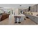 The stylish kitchen boasts gray cabinets, a large island with bar seating, flowing seamlessly into a cozy living area at 9710 Hiking Ave, Las Vegas, NV 89166