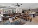 Comfortable open-concept living room with a large brown leather sofa and access to an open kitchen and outdoor patio at 9710 Hiking Ave, Las Vegas, NV 89166
