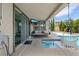 Covered patio next to pool with mounted TV, cushioned seating, and hanging chair at 9710 Hiking Ave, Las Vegas, NV 89166