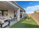 Inviting covered patio with comfortable seating, a hot tub, and a well-manicured artificial grass lawn at 10057 Matter Overlook Dr, Las Vegas, NV 89178