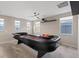 Spacious game room features a casino table, ceiling fan, and natural lighting from multiple windows at 10057 Matter Overlook Dr, Las Vegas, NV 89178