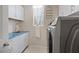Well-organized laundry room with white cabinets, a utility sink, countertop and a front-loading washer and dryer at 10057 Matter Overlook Dr, Las Vegas, NV 89178