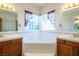 Bathroom featuring a central soaking tub with dual sink vanities and a corner window at 10140 W Tropical Pkwy, Las Vegas, NV 89149