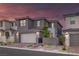 Two-story gray home boasts a brick driveway, manicured landscaping, and a spacious two-car garage at 2246 Bird Of Prey St, Las Vegas, NV 89138