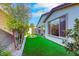 The side yard is landscaped with artificial turf, trees, and decorative rock features at 2386 Millergrove Ave, North Las Vegas, NV 89086