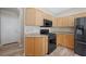 Bright kitchen featuring wood cabinets, granite countertops, and a modern black refrigerator and stove at 245 Homesteader Ct, Henderson, NV 89052