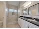 Stylish bathroom featuring double sinks, black granite countertops, and a walk-in shower at 2455 Silver Blossom Ln, Henderson, NV 89052