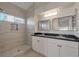 Modern bathroom featuring double sinks, black granite countertops, and tiled walk-in shower at 2455 Silver Blossom Ln, Henderson, NV 89052