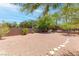 Expansive backyard featuring desert landscaping and a seating area with a wall and trees at 2799 Alnwick Ct, Henderson, NV 89044