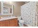 Well-lit bathroom with a shower featuring patterned curtain, wood vanity, and decorative mirror at 2799 Alnwick Ct, Henderson, NV 89044