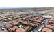 Wide aerial shot showcasing the community's red-tiled roofs, carports, mature trees, pool, nearby highway, and city views at 3360 Cactus Shadow St # 203, Las Vegas, NV 89129