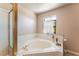 Corner bathtub with tiled surround, glass-enclosed shower, and window at 4378 Cherrystone Ct, Las Vegas, NV 89121