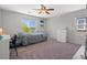 Bright bedroom features a ceiling fan, neutral walls and carpet, and a window overlooking the landscape at 4511 Stardusk Falls Ave, North Las Vegas, NV 89084