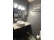 A modern bathroom with a single sink, dark vanity, and gray walls at 5804 Balzar Ave, Las Vegas, NV 89108