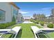 Lawn and landscaped backyard featuring lounge chairs, outdoor kitchen, and meticulously designed landscaping at 6184 Willow Rock St, Las Vegas, NV 89135
