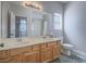 Bathroom with double sinks, wooden cabinets, a large mirror, and tile flooring at 6235 Westwind Rd, Las Vegas, NV 89118