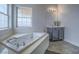 Bright bathroom features a large soaking tub, gray vanity, and a window for natural light at 6235 Westwind Rd, Las Vegas, NV 89118