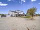Exterior view featuring a spacious yard, covered patio, and well-maintained landscaping with mature tree at 6235 Westwind Rd, Las Vegas, NV 89118