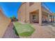 Featuring a well-maintained putting green, desert landscaping, covered patio, and privacy fence at 7380 Abundant Harvest Ave, Las Vegas, NV 89131