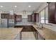 Gourmet kitchen with stainless appliances, granite counters, tile backsplash, and dark wood cabinets at 7380 Abundant Harvest Ave, Las Vegas, NV 89131