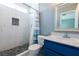 Stylish bathroom with modern tiled shower featuring a built-in shelf and a vanity with a blue cabinet at 7728 Barbican Ct, Las Vegas, NV 89147