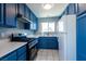 Well-lit kitchen equipped with blue cabinets, modern appliances, and a window offering natural light at 7728 Barbican Ct, Las Vegas, NV 89147