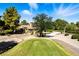 A beautiful backyard view of a residence on the golf course with mature trees and a glimpse of a garden at 7988 Harbour Towne Ave, Las Vegas, NV 89113