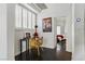Bright hallway with hardwood floors leads to bedroom; features small desk, unique art, and natural light from shuttered window at 7988 Harbour Towne Ave, Las Vegas, NV 89113