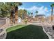 Lush backyard oasis featuring a pool, palm trees, green turf, and rock landscaping, perfect for outdoor living at 8320 Deer Springs Way, Las Vegas, NV 89149