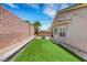This backyard has a manicured lawn area, seating area, tall palm trees, and privacy walls at 8836 Martin Downs Pl, Las Vegas, NV 89131