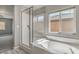 Bright bathroom featuring a soaking tub, glass-enclosed shower, and a window providing natural light at 10116 Nash Peak Ave, Las Vegas, NV 89166