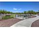Community dog park with gravel and grass featuring dog waste station, seating, and trees at 10116 Nash Peak Ave, Las Vegas, NV 89166