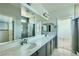Bathroom featuring dual sinks, large mirrors, a walk-in shower and modern lighting at 10271 Bark Pine Ct, Las Vegas, NV 89166
