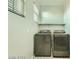 Laundry room with modern washer and dryer and a shelf for storage at 10271 Bark Pine Ct, Las Vegas, NV 89166