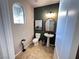 Modern powder room featuring a pedestal sink, stylish mirror, and contrasting accent wall with natural light at 10383 Andele Ave, Las Vegas, NV 89166