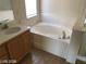 Bathroom featuring a soaking tub, single sink vanity, and neutral tile flooring, creating a relaxing and functional space at 1083 Sterling Peak St, Las Vegas, NV 89110