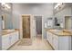 Bright bathroom featuring double sinks, a glass shower, neutral tile flooring, and a separate toilet area at 11 Morninglow Pass, Henderson, NV 89052