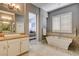 Bright bathroom featuring a soaking tub with pebble surround and a vanity with a marble countertop at 11 Morninglow Pass, Henderson, NV 89052