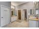Bright bathroom featuring double sinks, a glass shower, neutral tile flooring, and a separate toilet area at 11 Morninglow Pass, Henderson, NV 89052