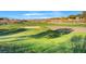 Wide shot of a well-maintained golf course with a sand trap and a red flag on the green at 11 Morninglow Pass, Henderson, NV 89052