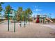 Community playground featuring swings, slides, and a shaded seating area in a sandy play space at 11 Morninglow Pass, Henderson, NV 89052